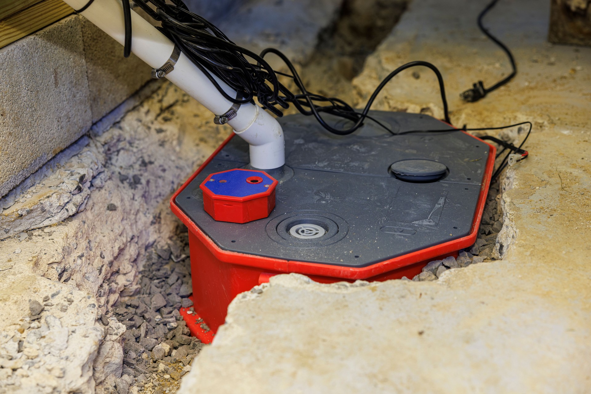 Basement waterproofing project reveals new drainage solution. Professional system combines red collection basin with advanced PVC network